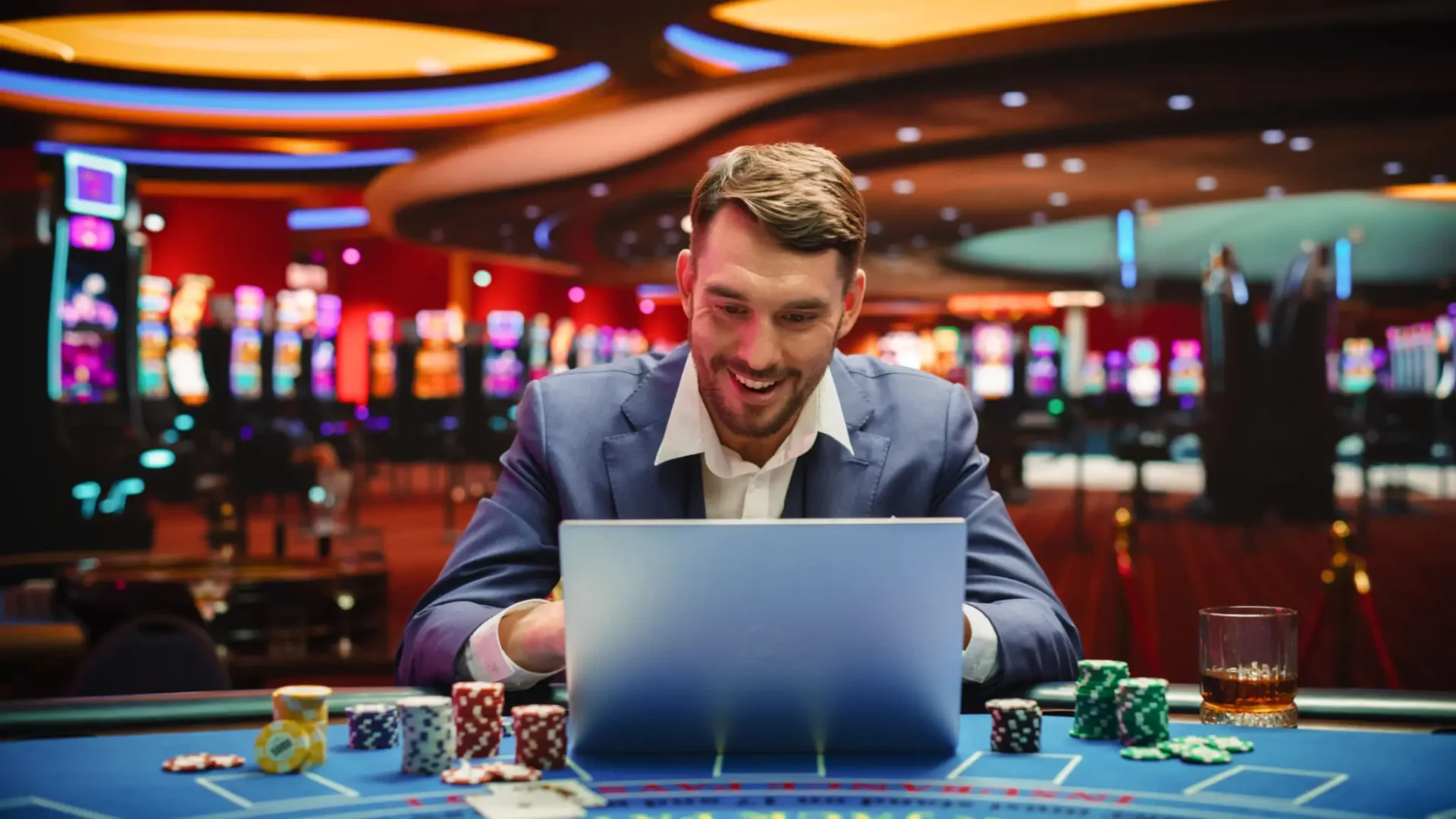 Smiling man at casino table with laptop